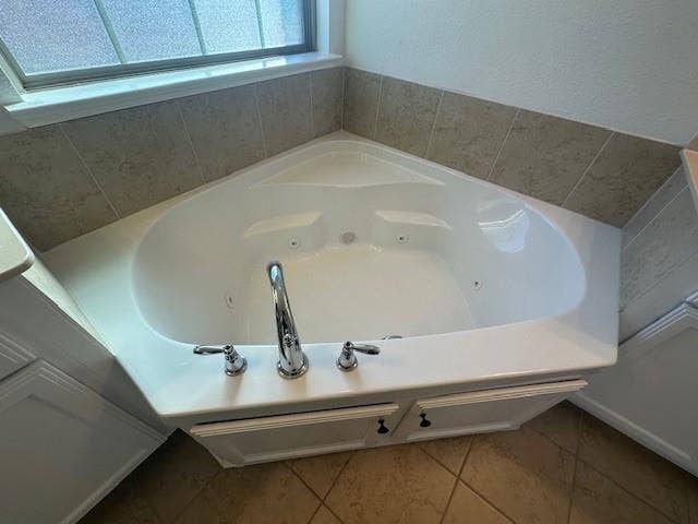 901 Brookville Court, Plano, TX 75074 Corner jetted tub with chrome fixtures, surrounded by neutral tile backsplash and white cabinetry