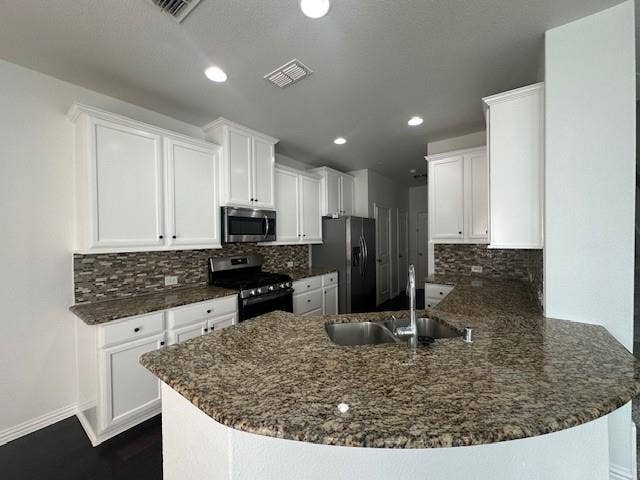 901 Brookville Court, Plano, TX 75074 Kitchen featuring white cabinetry, stainless steel appliances, mosaic tile backsplash, and a large breakfast bar with a double basin sink