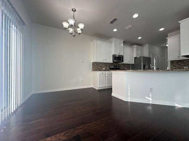 901 Brookville Court, Plano, TX 75074 Open-concept kitchen and dining area featuring dark wood-finish flooring, white cabinetry, integrated stainless steel appliances, a tiled backsplash, and recessed lighting