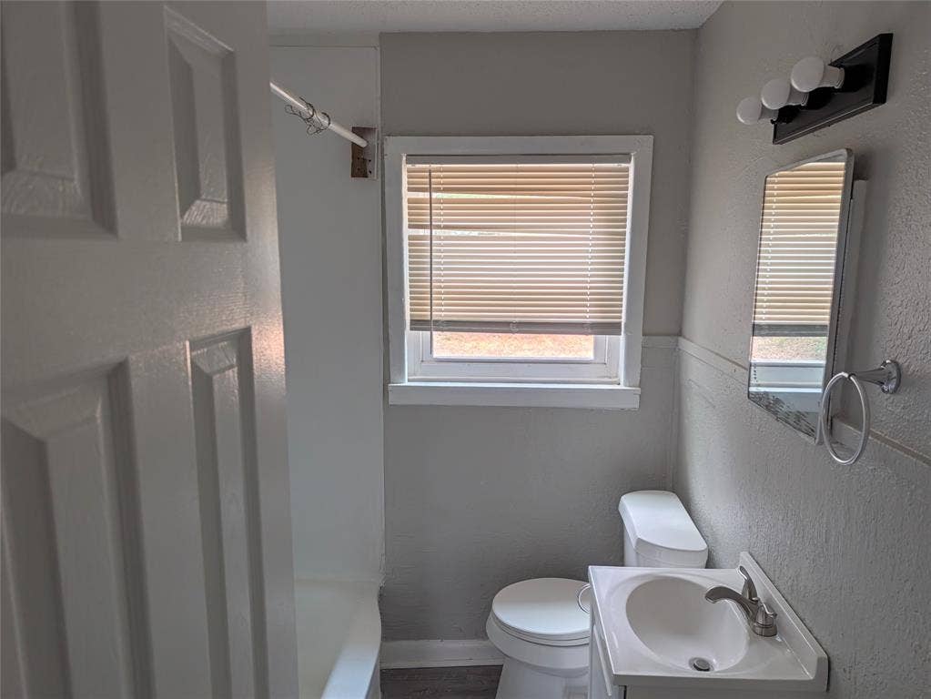 3409 Wood Avenue, Waco, TX 76711 White panel door, window with blinds, vanity sink, mirror, and wall-mounted light fixture
