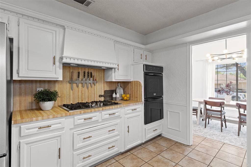 841 Villa Ridge Drive, Garland, TX 75043 White cabinetry with gold-tone hardware, wood-finish countertops, tile flooring, and a built-in double oven