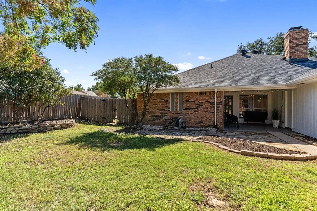 841 Villa Ridge Drive, Garland, TX 75043 Fenced backyard with a covered patio, brick chimney, and mature landscaping