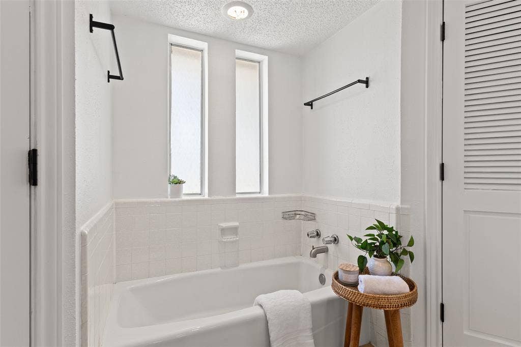 841 Villa Ridge Drive, Garland, TX 75043 Bathtub with white tile surround, chrome fixtures, and two vertical privacy windows
