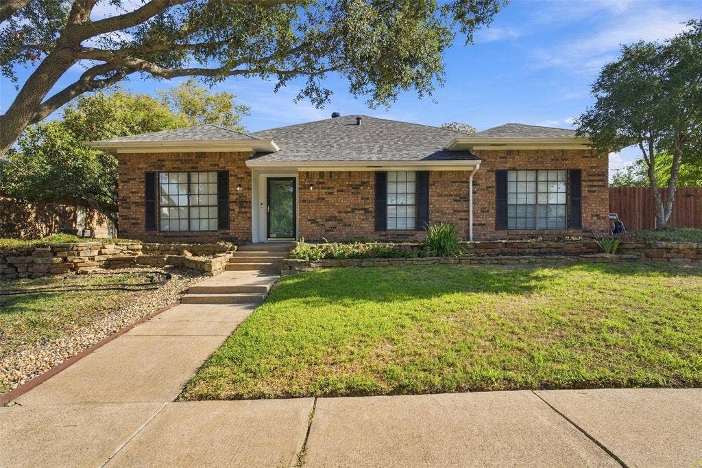 841 Villa Ridge Drive, Garland, TX 75043 Brick exterior with dark shutters, stepped concrete walkway, tiered stone landscaping, and a manicured lawn