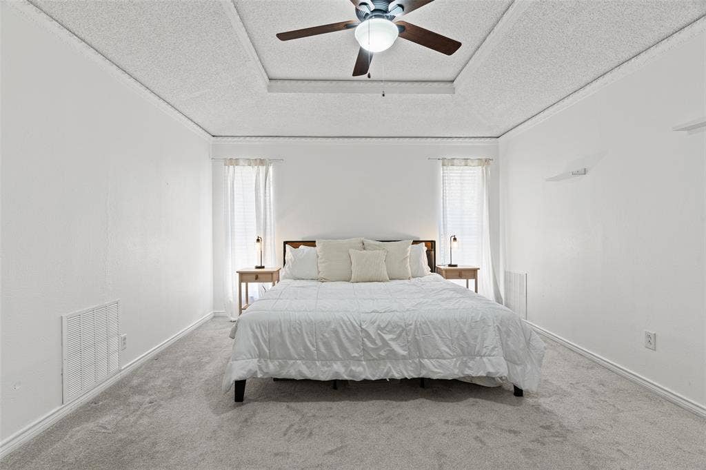 841 Villa Ridge Drive, Garland, TX 75043 Spacious primary bedroom with soaring coffered ceilings, ceiling fan with integrated lighting, and abundant natural light from dual windows