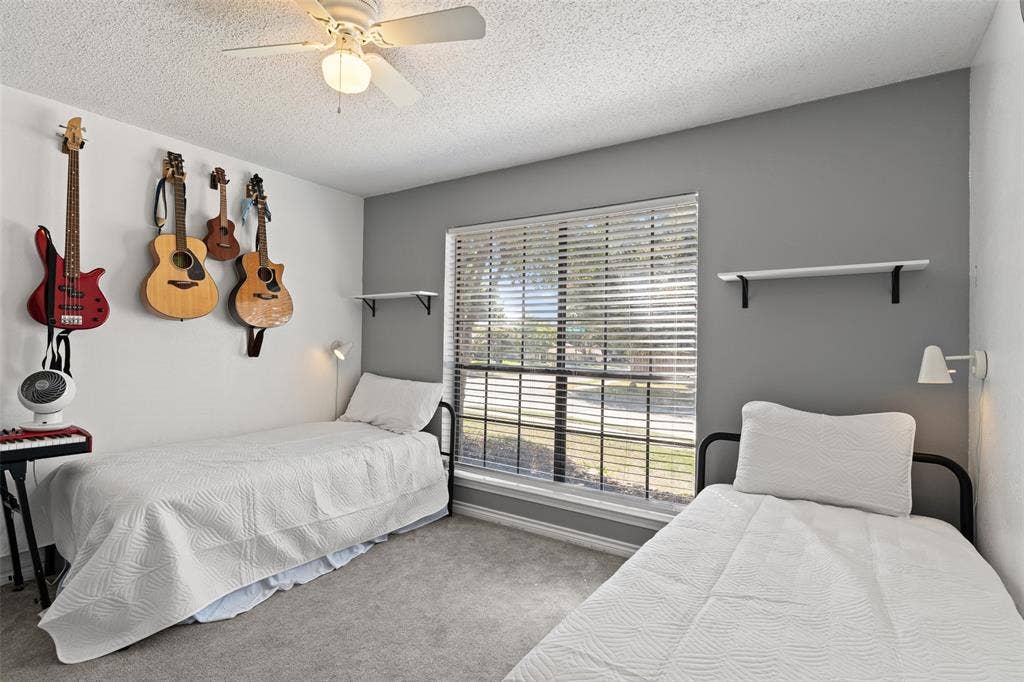 841 Villa Ridge Drive, Garland, TX 75043 Textured carpeting, window with horizontal blinds, built-in wall shelving, and ceiling fan with integrated lighting