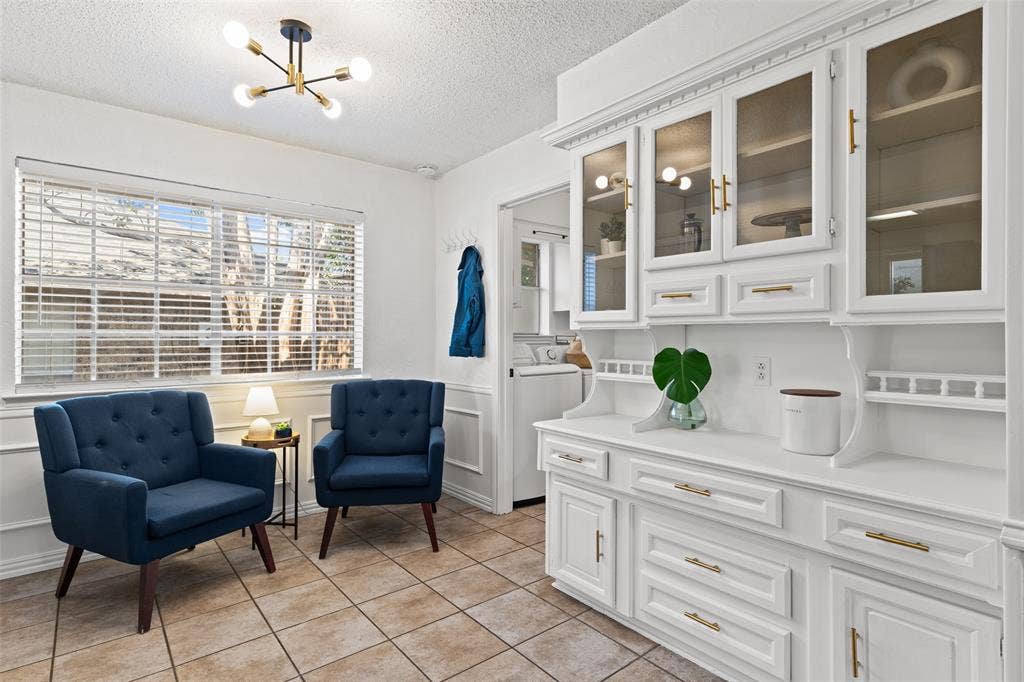 841 Villa Ridge Drive, Garland, TX 75043 White built-in cabinetry with glass-front upper doors and gold-finish hardware, tile flooring, and a large window with blinds