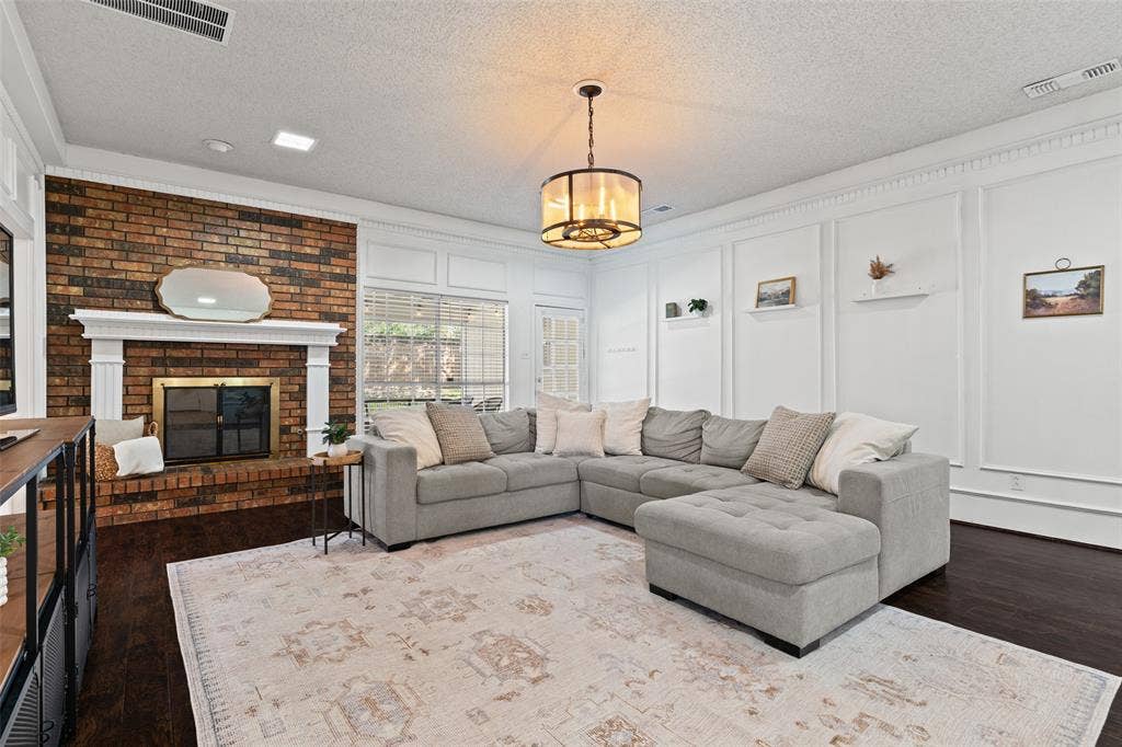 841 Villa Ridge Drive, Garland, TX 75043 Brick fireplace with a white mantel, dark wood-finish flooring, white panel molding, and a drum-style ceiling fixture