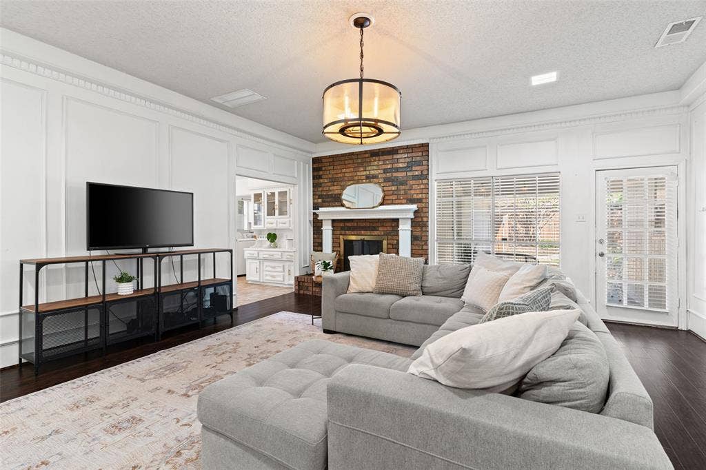 841 Villa Ridge Drive, Garland, TX 75043 Hardwood flooring, brick fireplace with a white mantel, white paneled walls, and a glass-paned door
