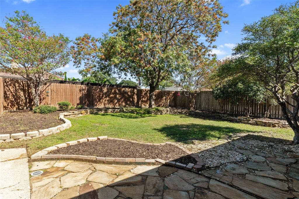 841 Villa Ridge Drive, Garland, TX 75043 Expansive backyard featuring a natural stone patio, wood privacy fencing, and established trees