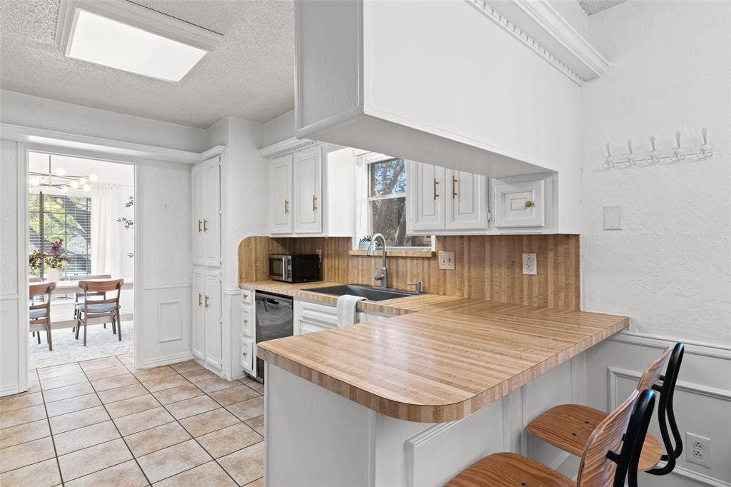 841 Villa Ridge Drive, Garland, TX 75043 Kitchen with tile flooring, white cabinetry, a wood-finish countertop, and a built-in dishwasher