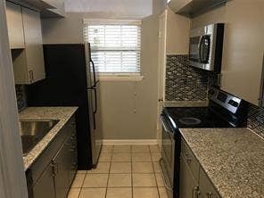 Kitchen featuring ceramic tile flooring, stainless steel sink, light-toned cabinetry, and granite-style countertops