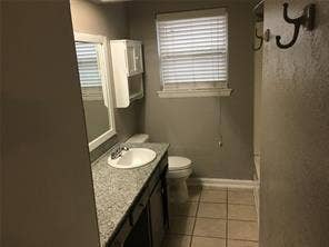 Bathroom featuring a vanity with an integrated sink, a window with blinds, and tile flooring