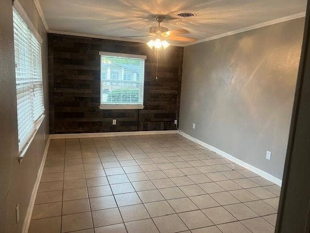 Tile flooring, accent wall with wood paneling, ceiling fan with integrated lighting, window with blinds, and crown molding