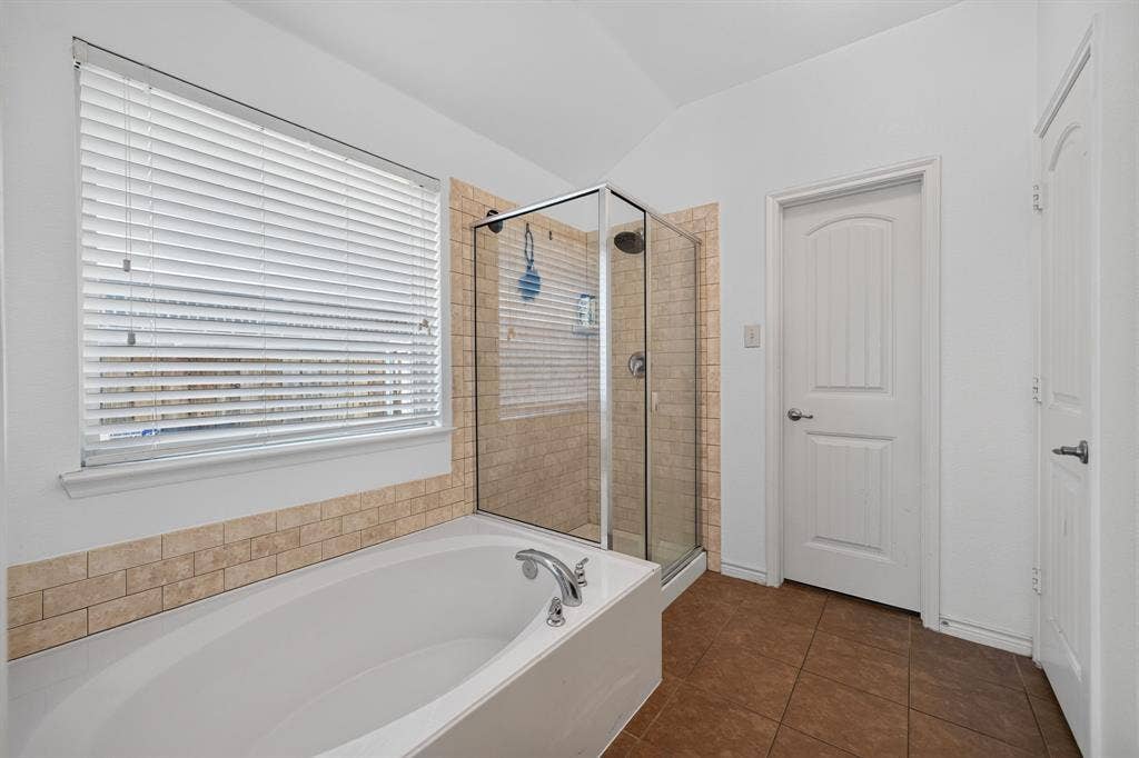 1048 Mercury Drive, Lavon, TX 75166 Soaking tub with chrome fixtures, glass-enclosed shower, and subway tile surround