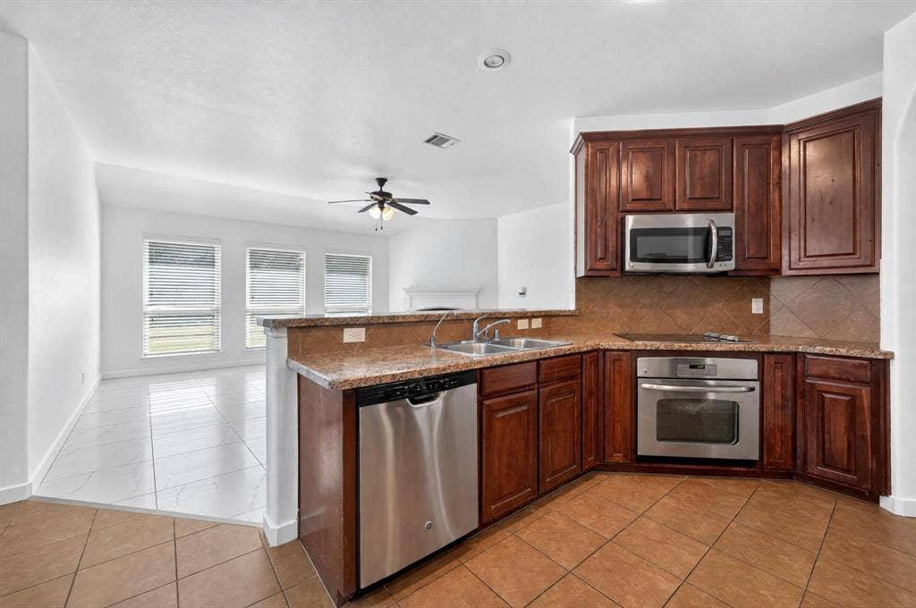1048 Mercury Drive, Lavon, TX 75166 Kitchen featuring dark wood-finish cabinetry, stainless steel appliances, and a tiled backsplash