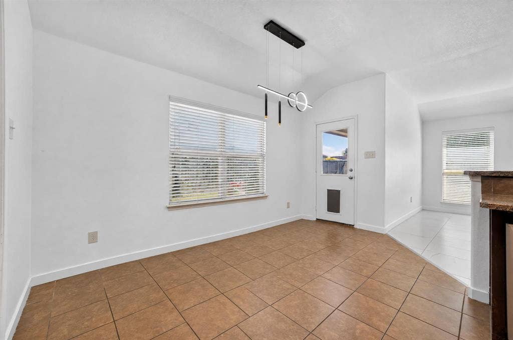 1048 Mercury Drive, Lavon, TX 75166 Tile flooring in a neutral tone, modern linear pendant light fixture, a window with blinds, and a door providing exterior access