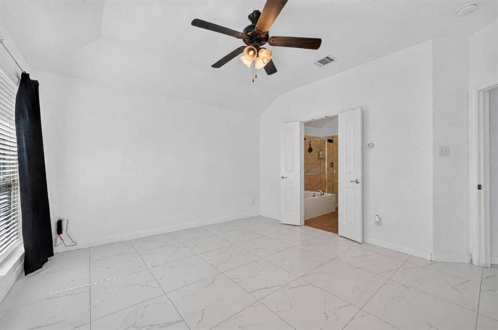 1048 Mercury Drive, Lavon, TX 75166 Vaulted ceiling with a ceiling fan, white tile flooring, and double doors opening to a bathroom with a soaking tub and shower