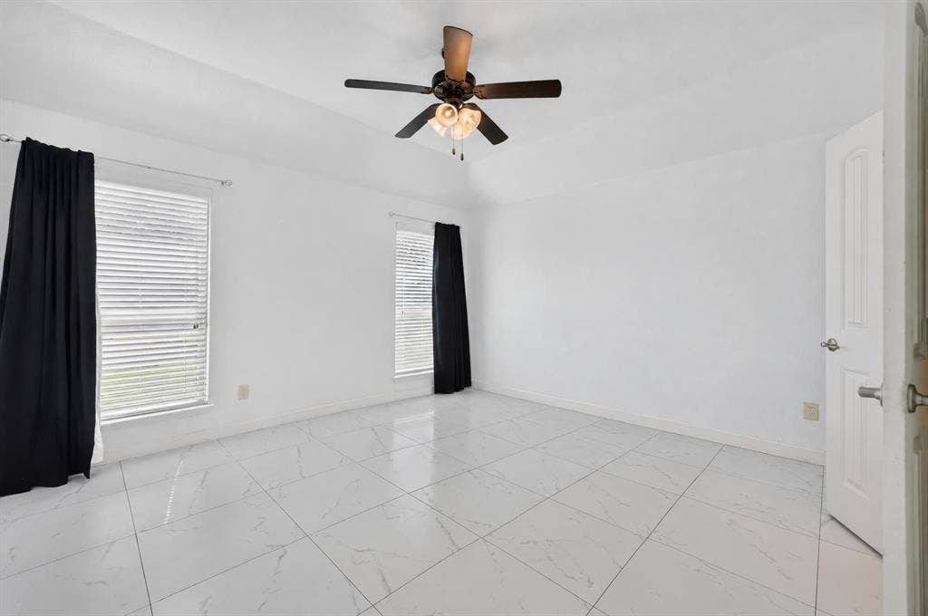 1048 Mercury Drive, Lavon, TX 75166 Vaulted ceiling with a ceiling fan, two windows with blinds, and white tile flooring