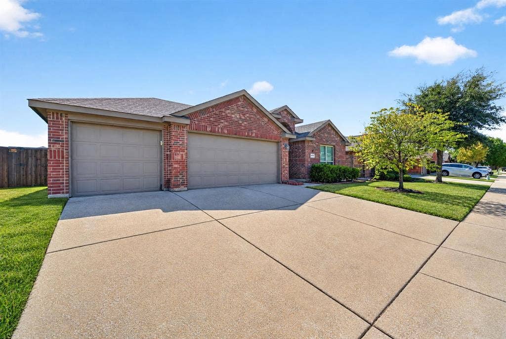1048 Mercury Drive, Lavon, TX 75166 Brick exterior with a three-car garage, concrete driveway, and front lawn landscaping