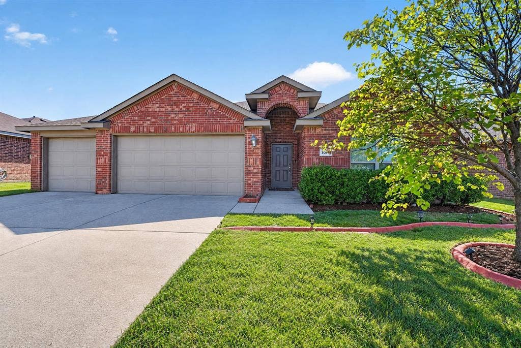 1048 Mercury Drive, Lavon, TX 75166 Brick exterior with archway entry, multi-car garage, concrete driveway, and landscaped front yard with mature tree