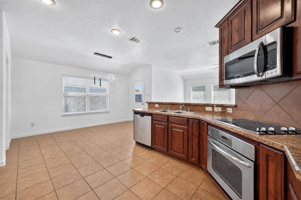 1048 Mercury Drive, Lavon, TX 75166 Kitchen with wood-finish cabinetry, stainless steel appliances, and a tiled backsplash