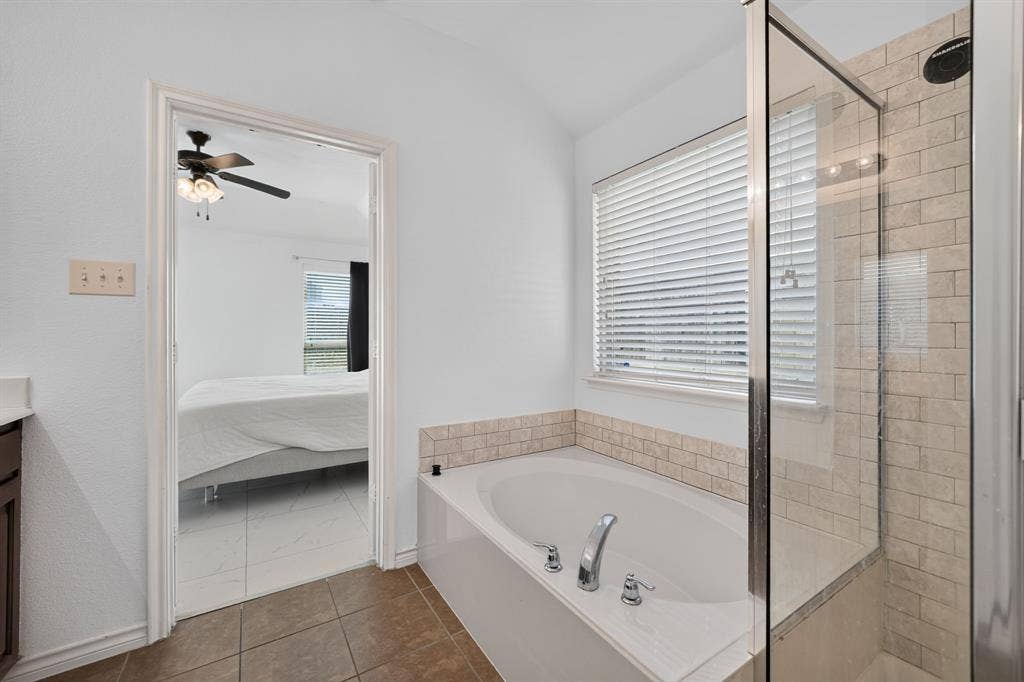 1048 Mercury Drive, Lavon, TX 75166 Built-in soaking tub with chrome fixtures, tiled surround, and separate glass-enclosed shower featuring subway tile