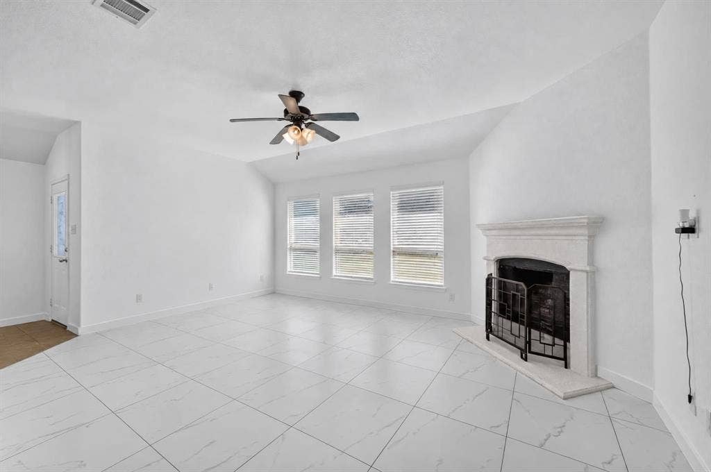1048 Mercury Drive, Lavon, TX 75166 Spacious room featuring white tile flooring, a fireplace with a decorative mantel, multiple windows with blinds, and a ceiling fan with integrated lighting