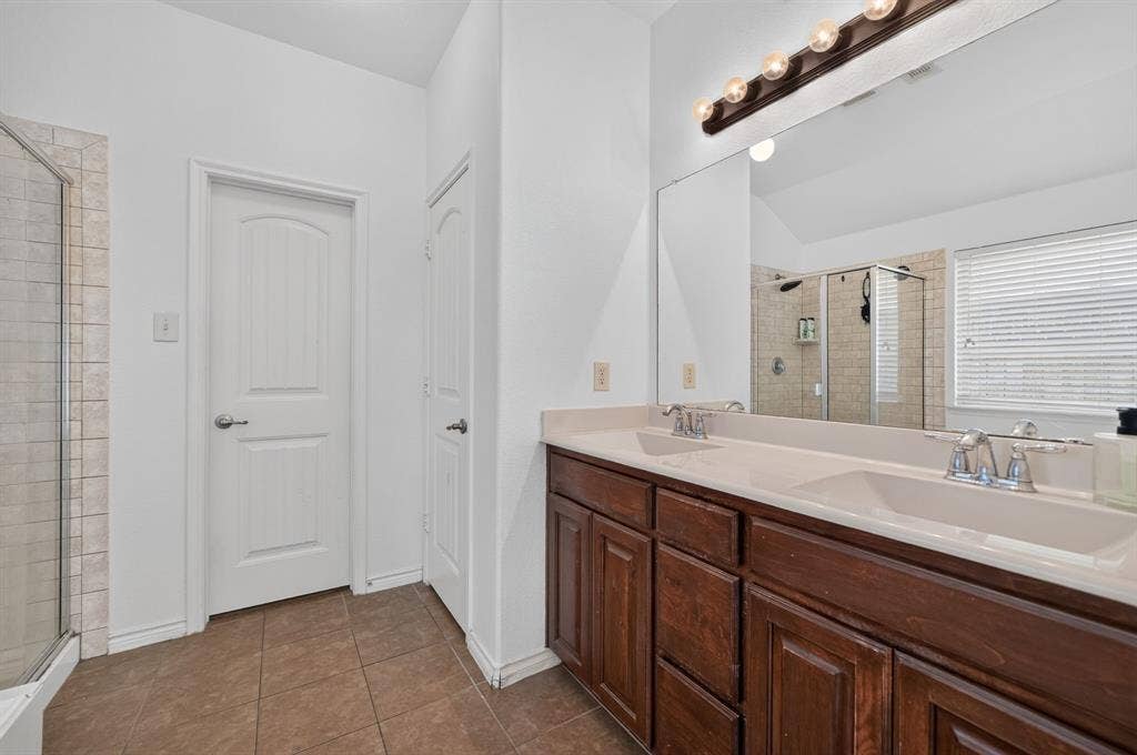 1048 Mercury Drive, Lavon, TX 75166 Double vanity with integrated sinks, wood-finish cabinetry, and a large wall-mounted mirror