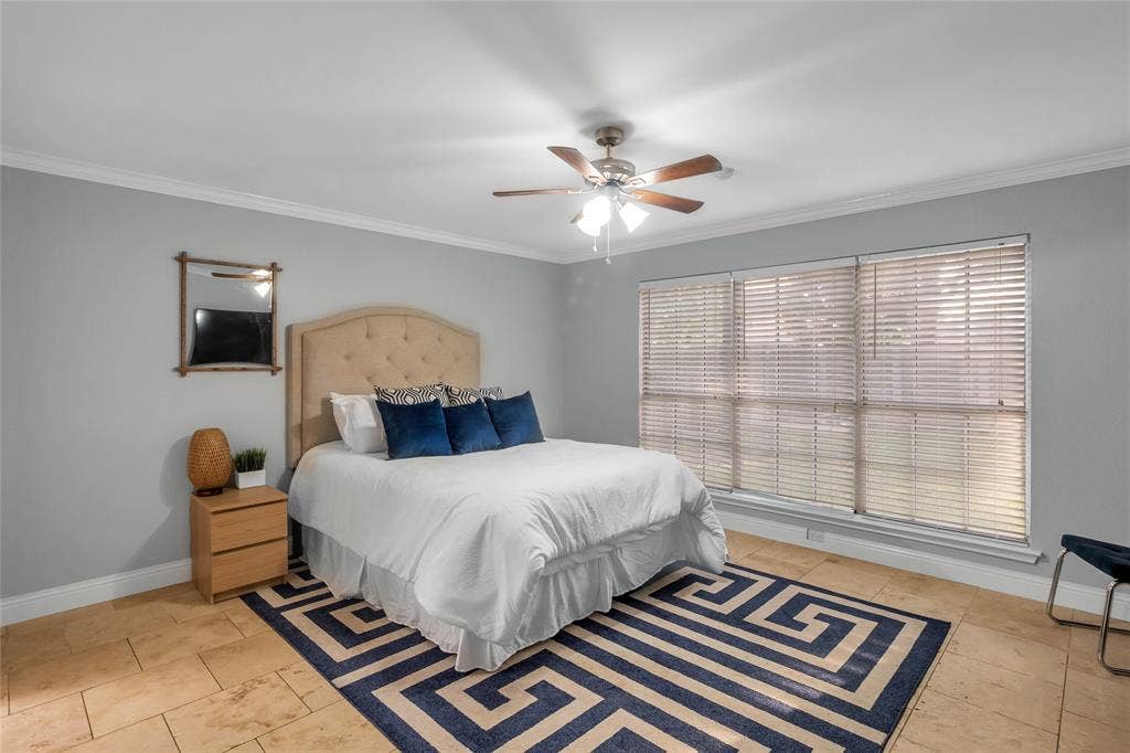 4523 Wescott Drive, Grand Prairie, TX 75052 Spacious primary bedroom featuring a wood-finish plank floor, ceiling fan with integrated lighting, arched upholstered headboard, and abundant natural light from triple-panel sliding glass doors with plantation shutters