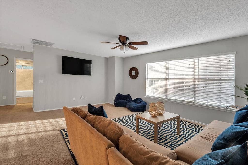 4523 Wescott Drive, Grand Prairie, TX 75052 Expansive living area featuring carpeted flooring, a ceiling fan, and multiple windows with blinds