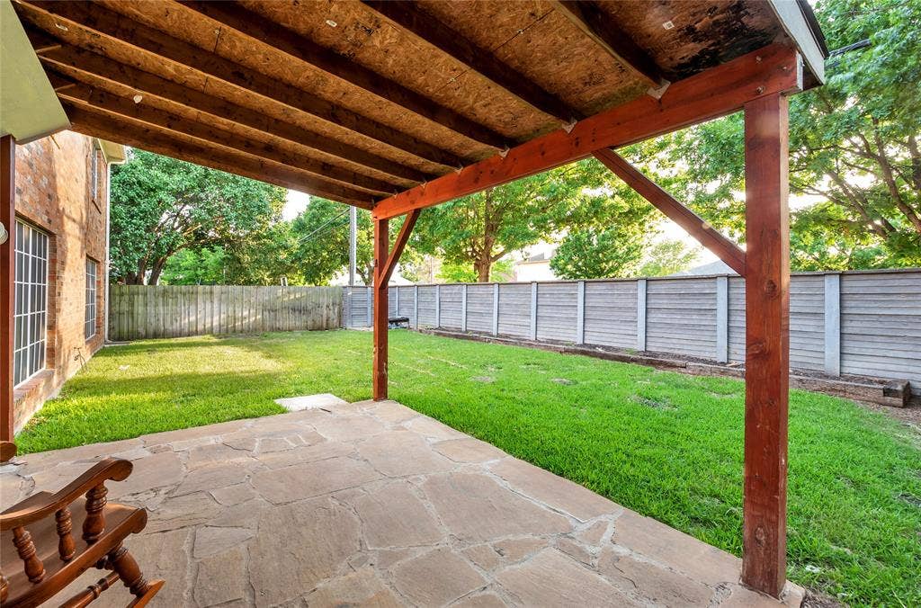 4523 Wescott Drive, Grand Prairie, TX 75052 Covered patio with flagstone flooring, bordered by a green lawn and privacy fencing