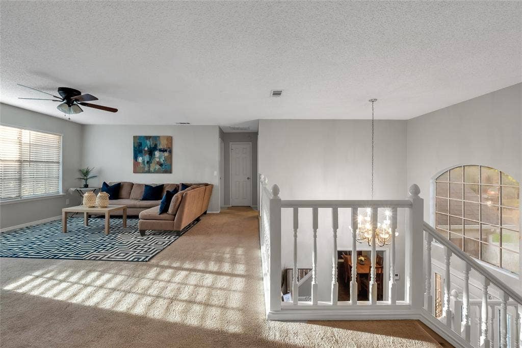 4523 Wescott Drive, Grand Prairie, TX 75052 Carpeted flooring, ceiling fan, white paneled door, and a white staircase with a chandelier