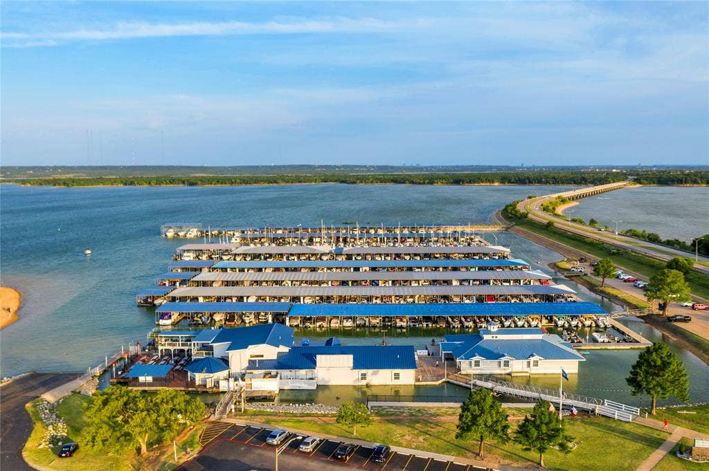4523 Wescott Drive, Grand Prairie, TX 75052 Expansive waterfront property featuring extensive boat slips, multiple dockside structures, a surrounding body of water, a nearby road, and shoreline landscaping