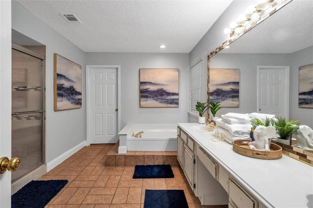 4523 Wescott Drive, Grand Prairie, TX 75052 Spacious bathroom featuring a large vanity with ample counter space, built-in soaking tub, walk-in shower with sliding glass door, and tile flooring