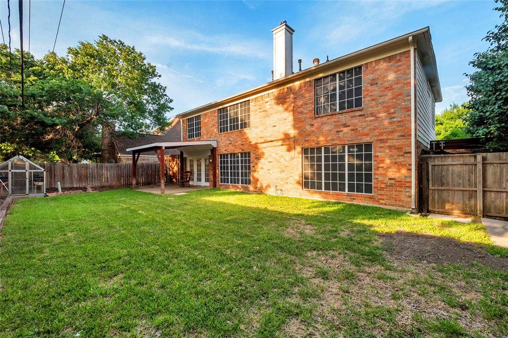 4523 Wescott Drive, Grand Prairie, TX 75052 Brick exterior with multiple pane windows, ground-level covered patio with wood supports, and an expansive lawn