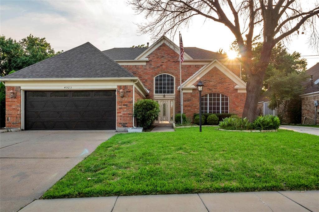 4523 Wescott Drive, Grand Prairie, TX 75052 Brick exterior with a dark shingle roof and a two-car garage