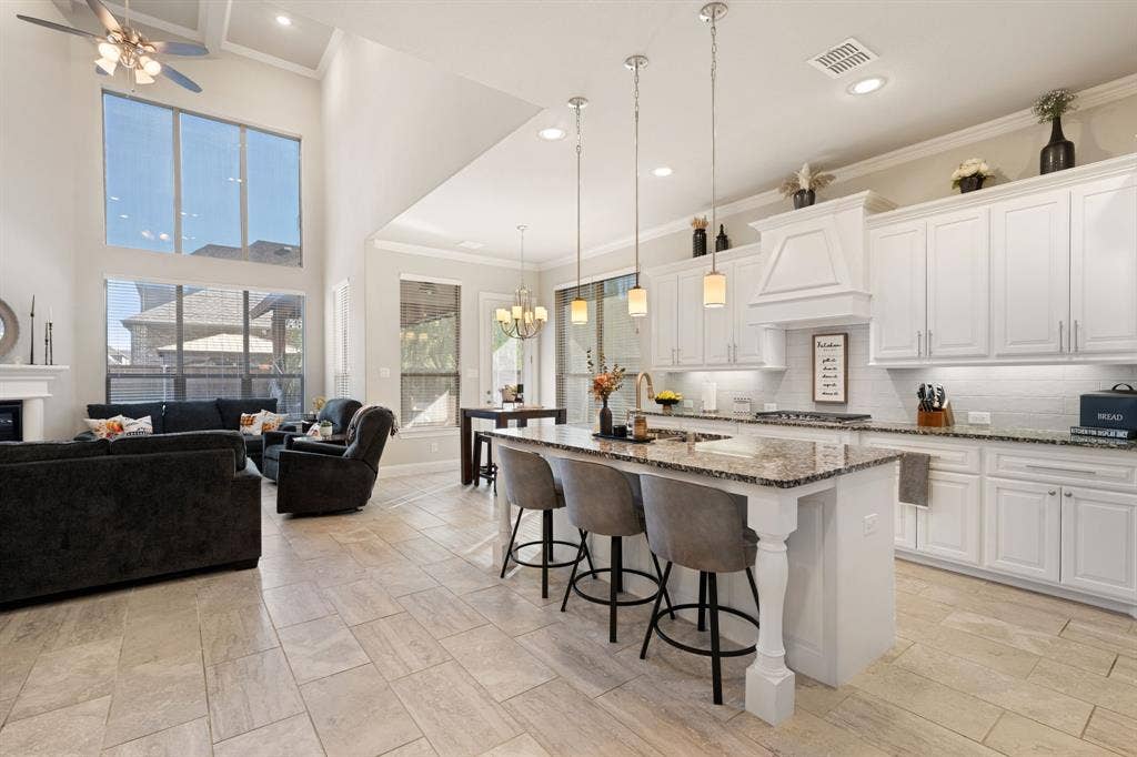 Open-concept living space with high ceilings, large windows, a fireplace, and light-toned tile flooring