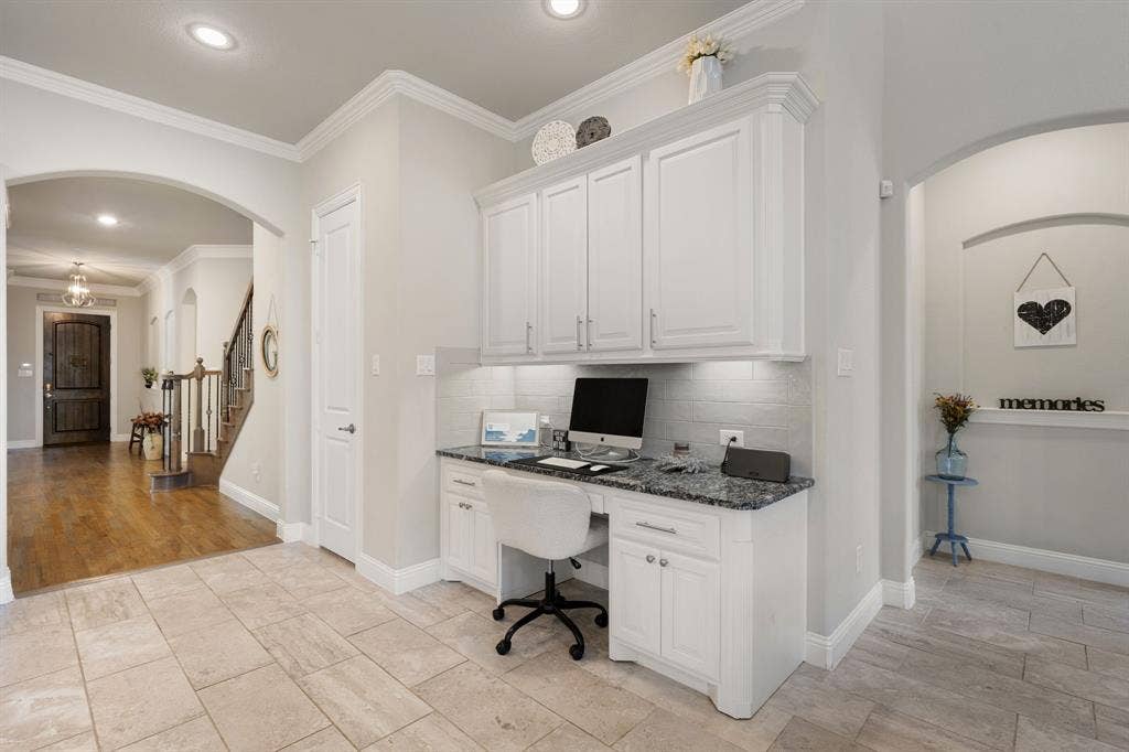 Built-in desk with white cabinetry, granite-style countertop, and subway tile backsplash