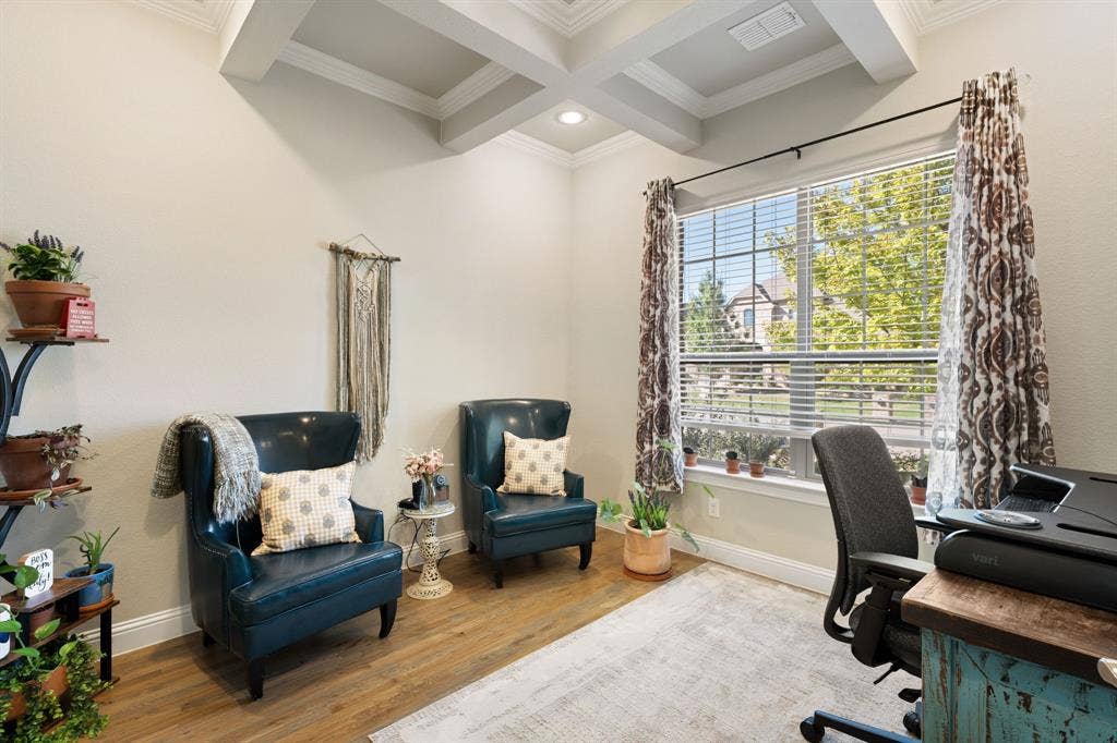 Coffered ceiling with recessed lighting, large window with blinds and patterned curtains, light-toned walls, and wood-finish flooring