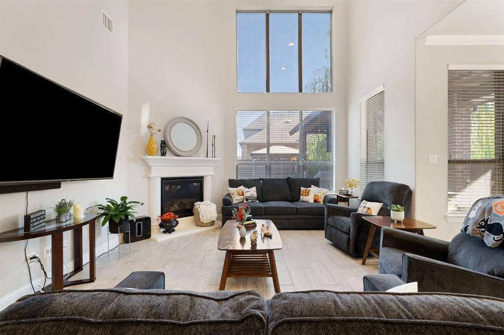 Living area featuring a floor-to-ceiling fireplace with a mantel, soaring ceilings, and a combination of large windows and transom windows