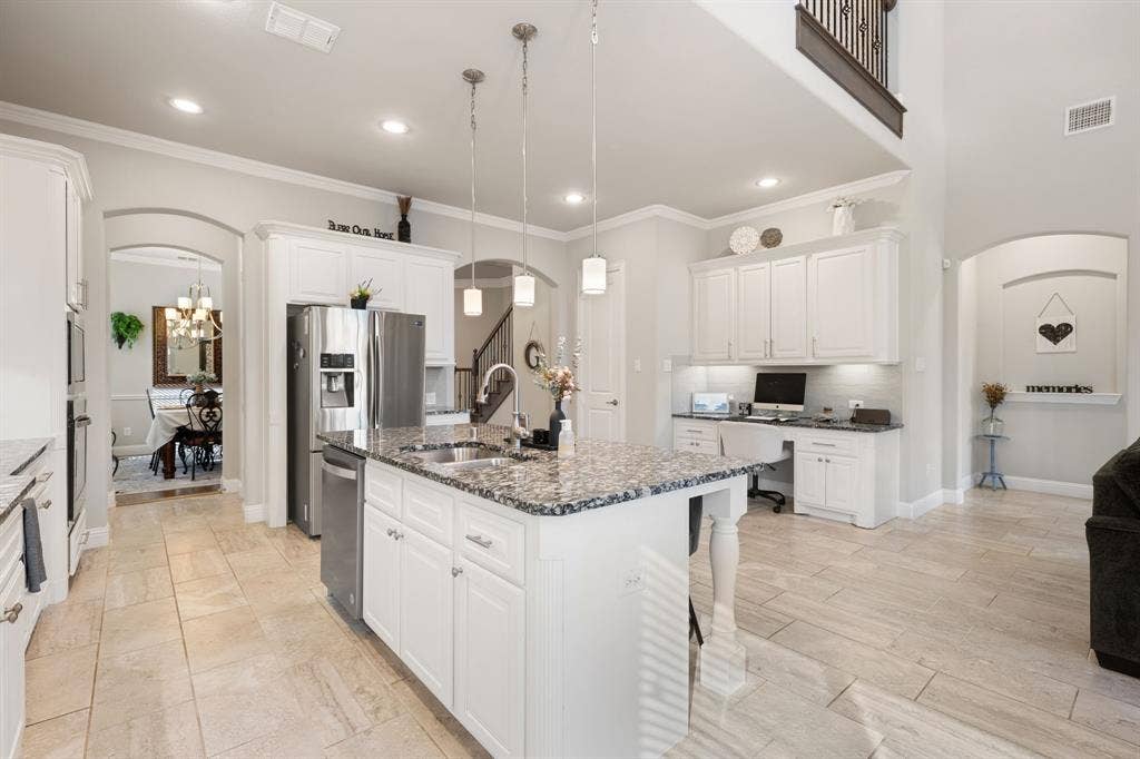 Kitchen featuring a large central island with granite countertop, white cabinetry, and stainless steel appliances