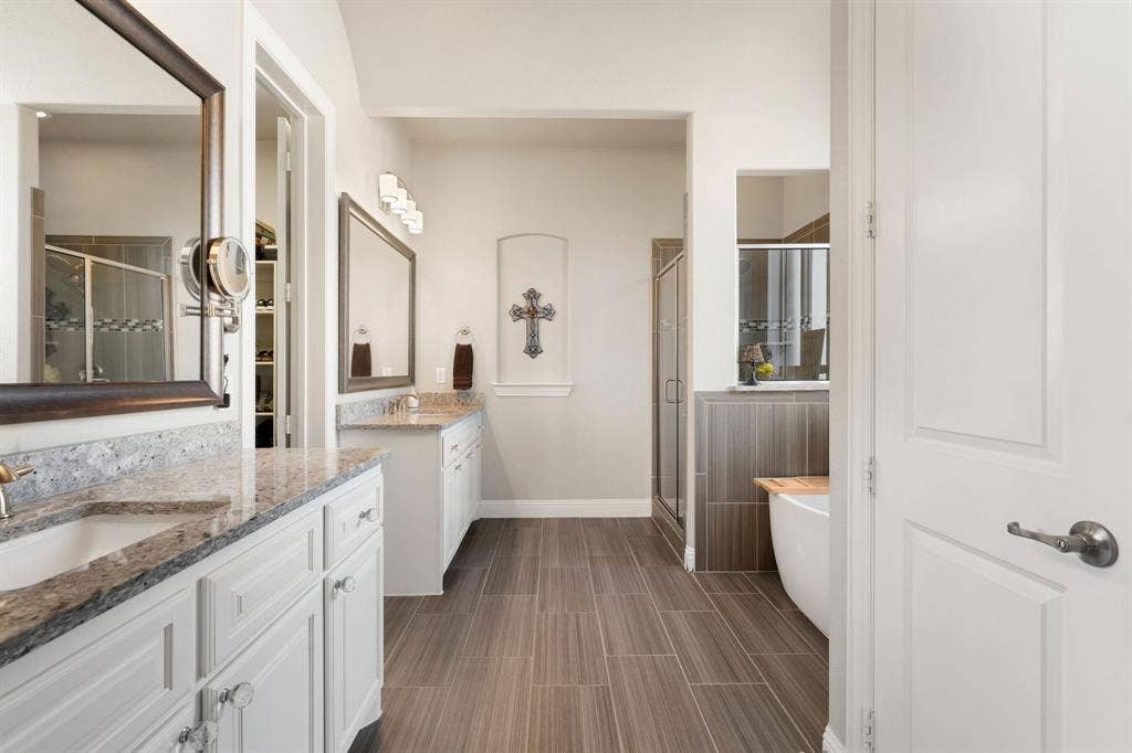 Dual vanities with undermount sinks, granite countertops, and white cabinetry
