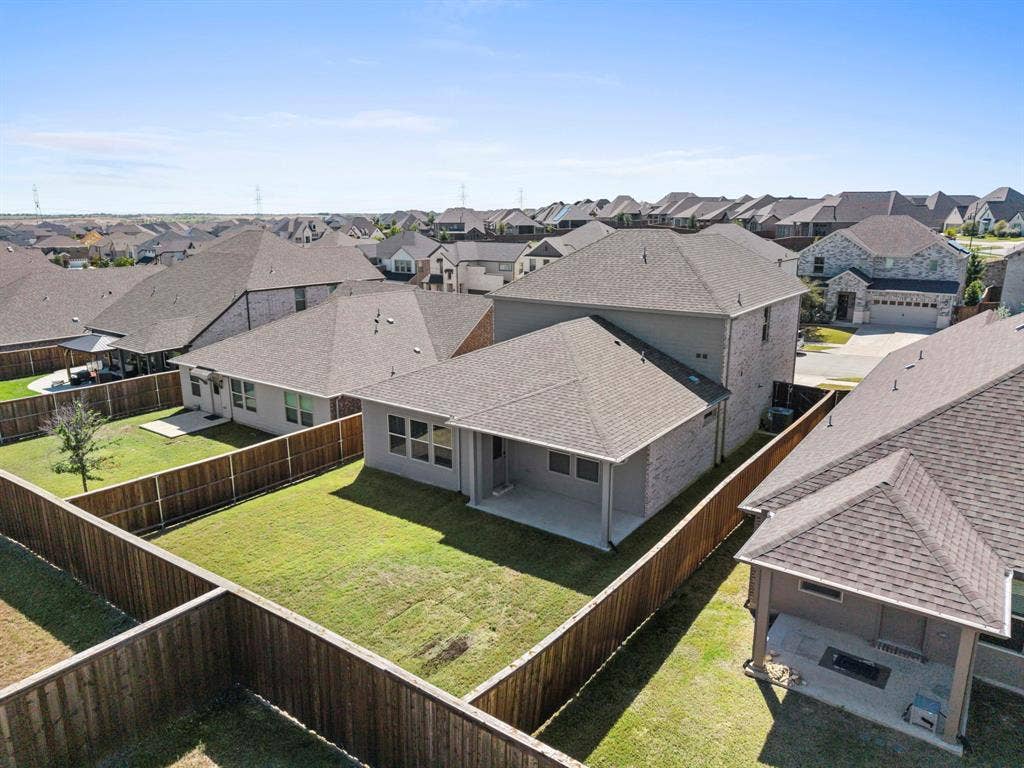 Expansive backyard with a manicured lawn, full wood fencing, and a concrete patio