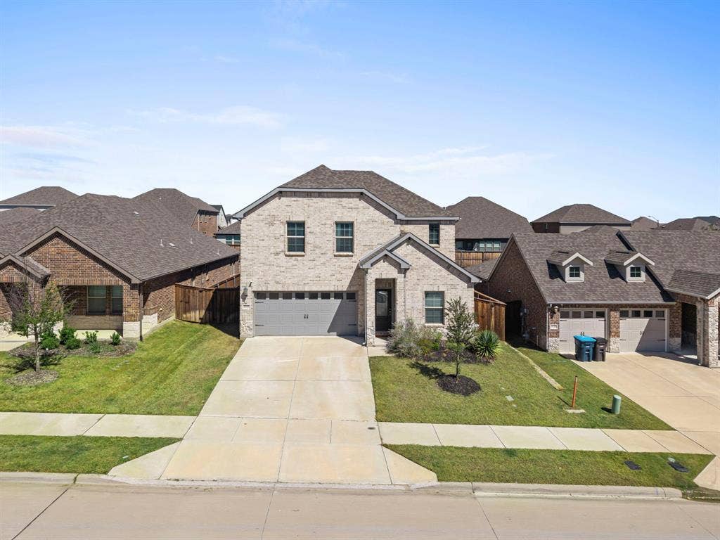 Brick exterior with stone accents, attached two-car garage, and a concrete driveway