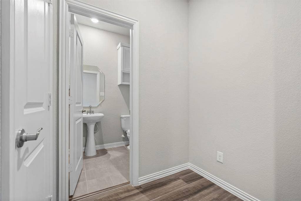 Wood-finish flooring with white trim and a neutral wall color