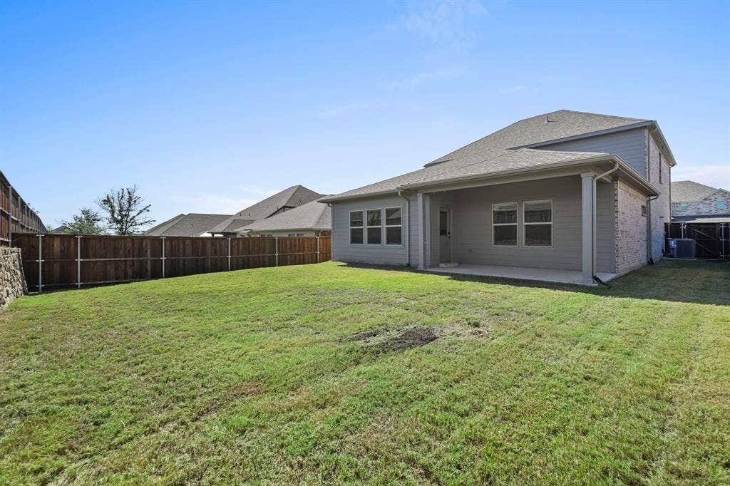 Expansive backyard with a wood privacy fence, concrete patio, and a covered porch