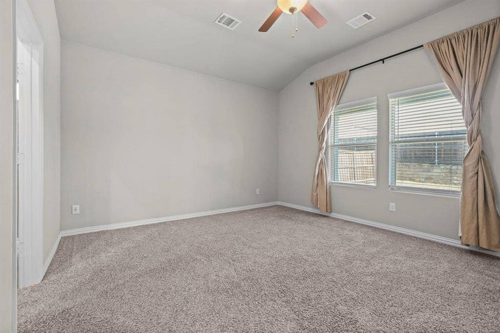 High ceilings with a ceiling fan, neutral carpet flooring, two windows with blinds, and light-colored walls
