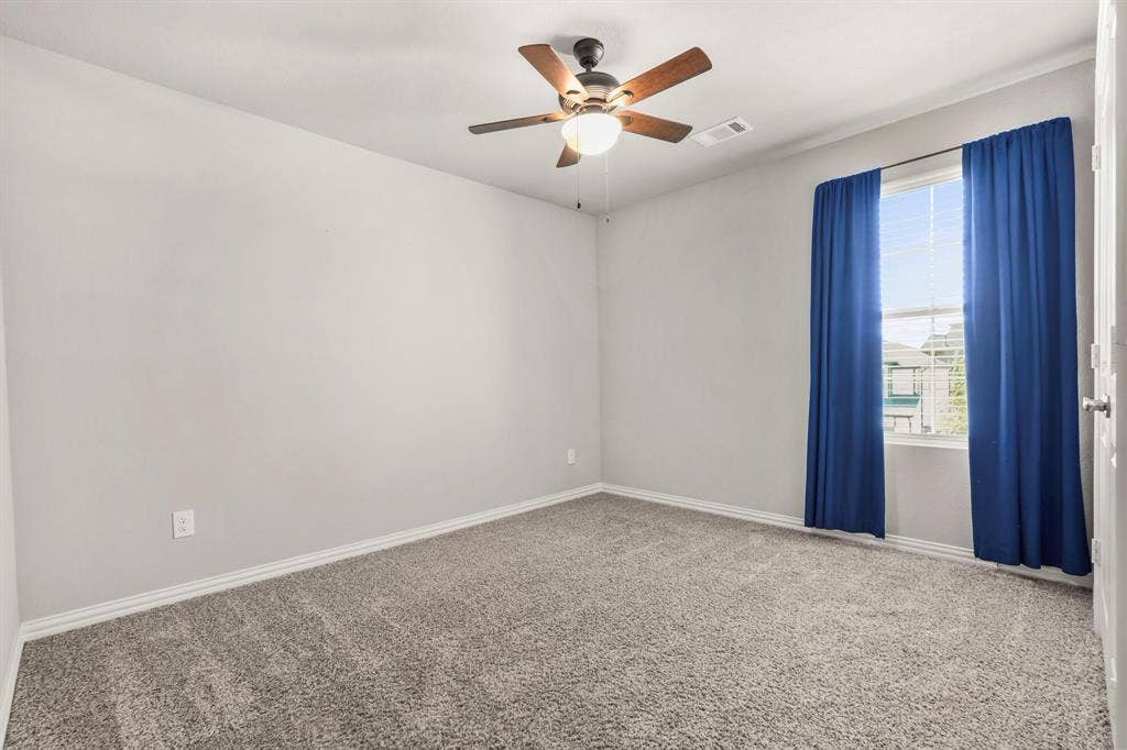 Neutral wall paint, ceiling-mounted light fixture, window with blinds, and gray carpet flooring