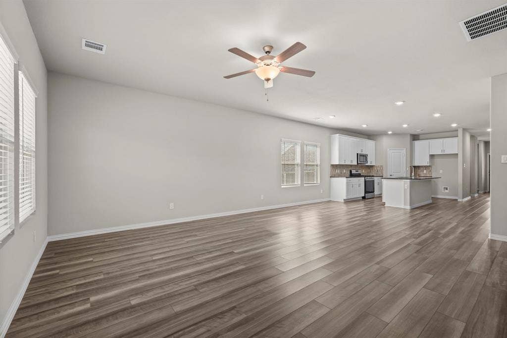 Open-concept living area with wood-finish flooring, white cabinetry, a kitchen island, and recessed lighting